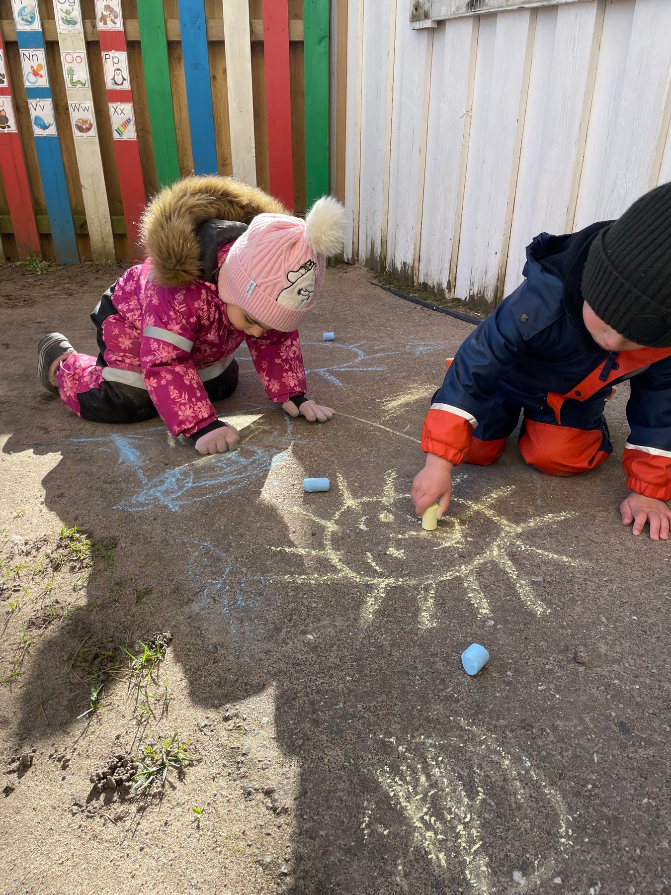 Barn ritar med kritor utomhus på Förskolan Sinbad